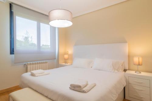 a bedroom with a white bed with two towels on it at APARTAMENTO Holidea OLMECA in Santander