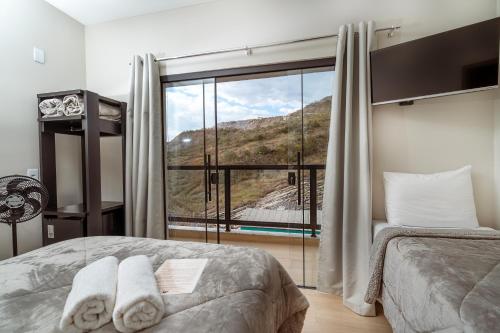 a bedroom with a bed and a large window at Pousada Canto da Montanha in São Thomé das Letras