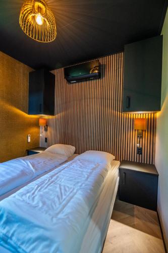 a bedroom with a large bed and two lamps at Wellnesslodge Merel jacuzzi sauna and privacy in Dalerveen