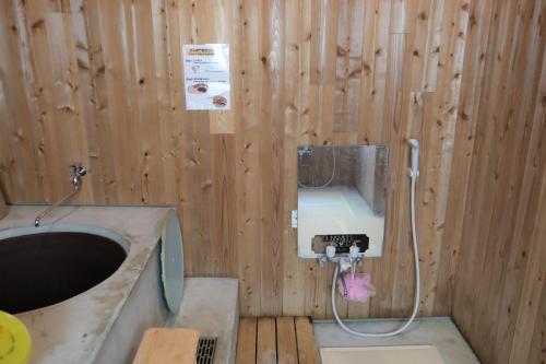 a bathroom with a sink in a wooden wall at 奈良吉野の小学校跡地ゲストハウス-五右衛門風呂体験-漫画図書室-卓球台-一棟貸し-素泊まり-吉野山天川村観光-Small inn attached to a historic school building in Zengi