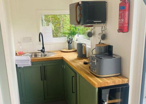 Kuchnia wyposażona jest w zielone szafki, umywalkę i kuchenkę mikrofalową. w obiekcie Watermill Leisure Park 