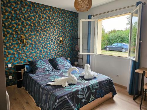 two swans on a bed in a bedroom with a window at Les chambres d'Estelle in Guécélard
