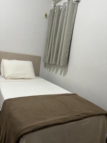 a bedroom with a bed with a pillow and curtains at HOTEL PORTO in Valença