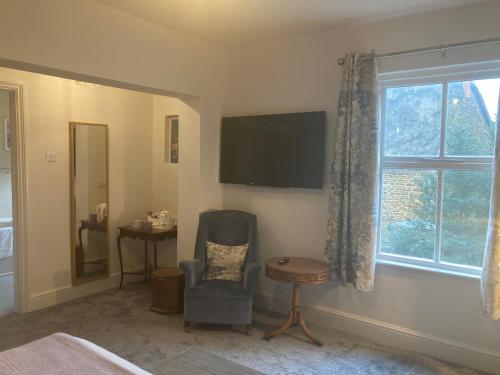 a bedroom with a chair and a tv and a window at Crick Cottage Rooms in Crick