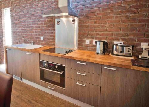 a kitchen with wooden cabinets and a brick wall at The Sherwood Hideaway Lodges 