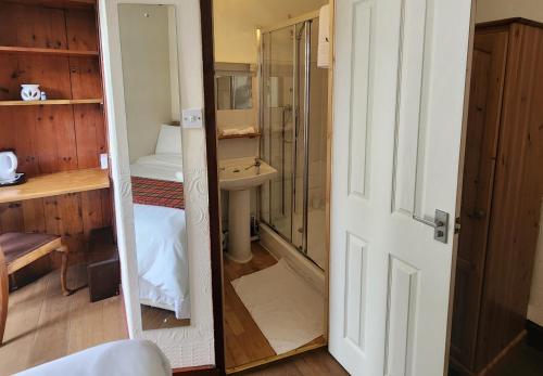 bagno con doccia, lavandino e specchio di The Retreat Hotel a Strathpeffer