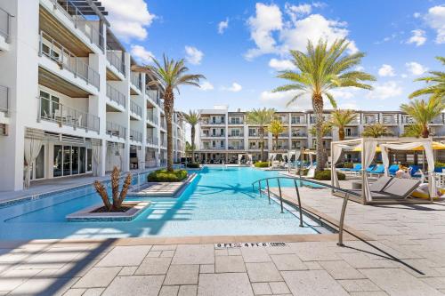 a swimming pool with palm trees in front of a building at Texas Two Step by 30A Escapes in Rosemary Beach