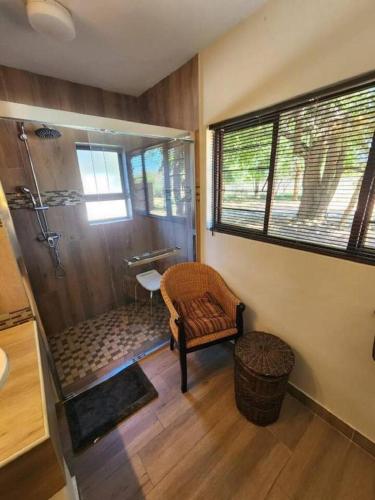 a bathroom with a shower and a chair and a window at Bateleur Lodge, Mabalingwe in Warmbaths
