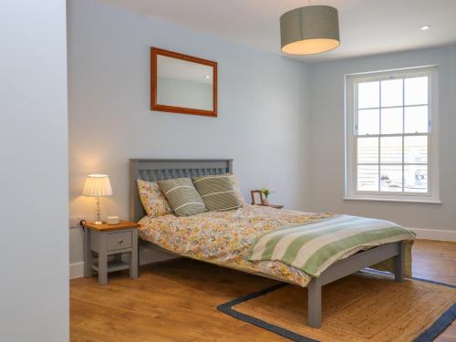 a bedroom with a bed and a nightstand and a window at The Seven Sands in Dymchurch