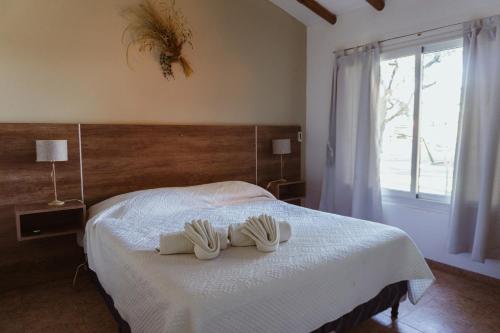 a bedroom with a bed with two white shoes on it at Cabañas "El Valle" in San Rafael