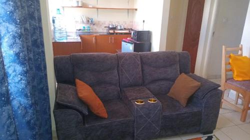 a blue couch with orange pillows in a living room at Georgia Furnished Apartments in Machakos