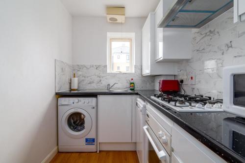 uma cozinha branca com uma máquina de lavar roupa em GuestReady - Parkside getaway in Britannia Village em Londres