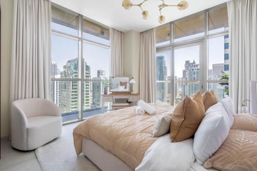a bedroom with a bed and a chair and large windows at GuestReady Holiday Homes - Boho Marina Dream in Dubai
