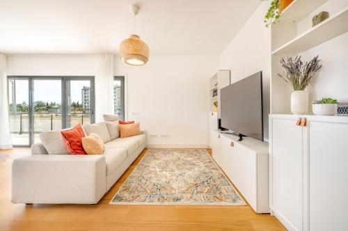 ein Wohnzimmer mit einem Sofa und einem TV in der Unterkunft GuestReady - Tranquil Seixal Haven in Seixal