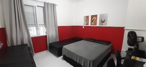 1 dormitorio con cama y pared roja en Kitnet em Guarujá - Pitangueiras (sem garagem), en Guarujá