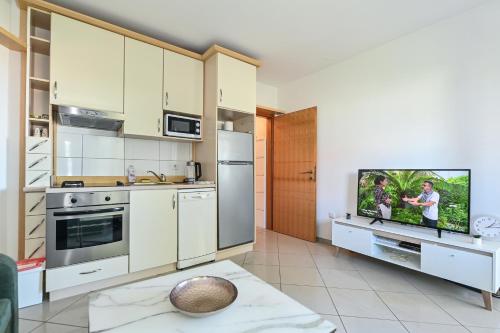 uma cozinha com armários brancos e uma televisão de ecrã plano em LaLee em Novalja