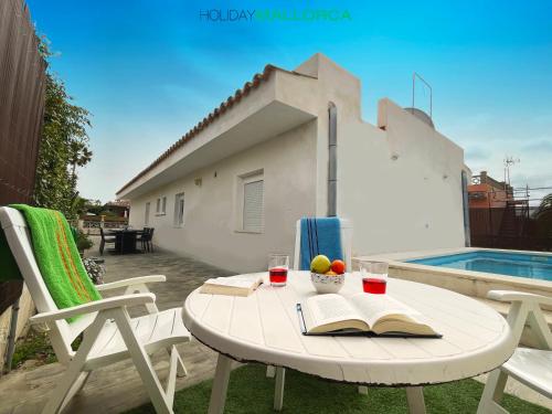 een tafel met een boek en twee stoelen en een zwembad bij Lakeside Plaza - Alcúdia Beach in Alcudia