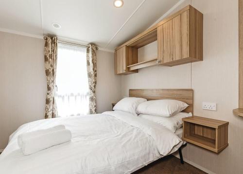 2 bedden in een kleine slaapkamer met een raam bij Bucklegrove Holiday Park in Rodney Stoke