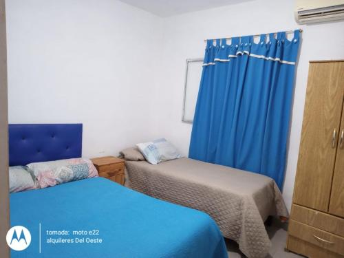 1 dormitorio con 2 camas y cortina azul en Alquileres del oeste en La Rioja