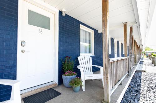 una casa azul con una puerta blanca y una silla blanca en Anchor Bay Inn and Suites en Sandusky