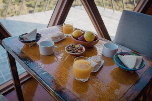 Una mesa con vasos de jugo de naranja y tazones de fruta. en Domos Zen, en Estancia Grande