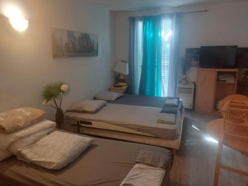 une chambre avec deux lits et une fenêtre avec des rideaux bleus dans l'établissement AJACCIO Beau Studio pour 3 a 4 pers en Plein Centre de la Vieille Ville Historique, à Ajaccio