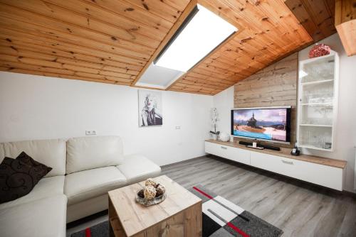 ein Wohnzimmer mit einem weißen Sofa und einem TV in der Unterkunft Appartement Gimpl - Entspannen, Wohlfühlen, Genießen in Fusch an der Glocknerstraße
