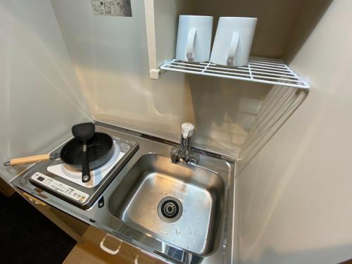 a small kitchen with a sink in a refrigerator at CityStay難波南 in Osaka