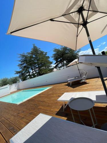 an umbrella sitting on a deck next to a swimming pool at Allivigne Rooms & Pool in Polignano a Mare