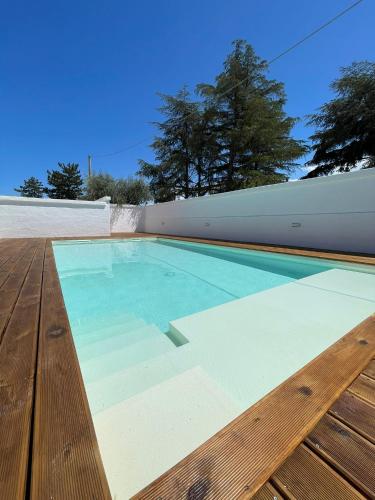 a swimming pool with blue water and a wooden deck at Allivigne Rooms & Pool in Polignano a Mare