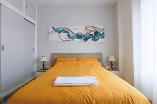 1 dormitorio con 1 cama amarilla y 2 toallas en Piso Del Mar Menor, en Los Nietos