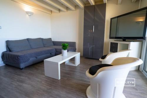 a living room with a couch and a flat screen tv at Vias-Plage - Appartement climatisé avec piscine face à la mer in Vias