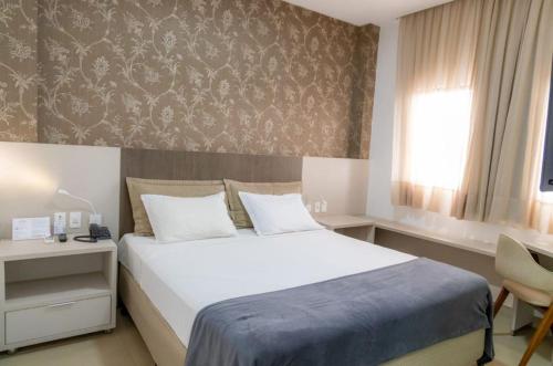 Un dormitorio con una gran cama blanca y una ventana en Brii Hotel en Araguaína