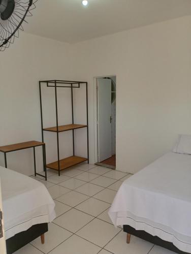 Habitación blanca con 2 camas y espejo. en Angelus Hotel & Estacionamento, en Campos dos Goytacazes