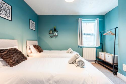 Duas camas num quarto com paredes azuis em Shamrock House- 2 BR House, Free Parking & WIFI em Ipswich