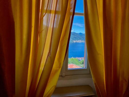 a window with a yellow curtain with a view of the ocean at Villa Diomira in Cannobio