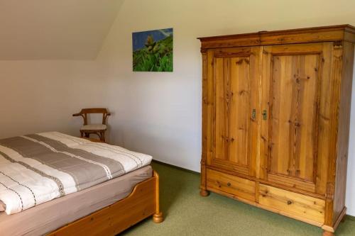 a bedroom with a bed and a wooden cabinet at Ferienwohnung SandSteinLand in Reinhardtsdorf