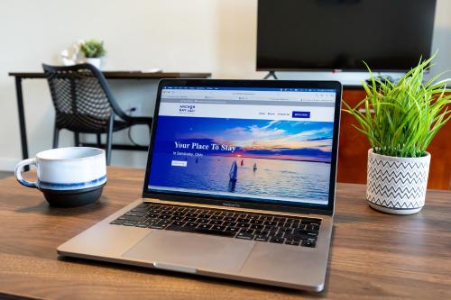 a laptop computer sitting on a desk with a cup of coffee at Anchor Bay Inn and Suites in Sandusky