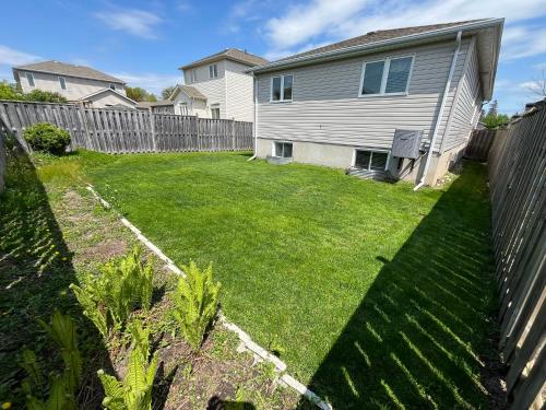 a yard with a fence in front of a house at Spacious and Charming Bungalow Retreat (Close to Many Amenities) in Kingston