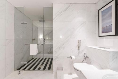 a white bathroom with a shower and a toilet at Emaar Residences Fashion Avenue, formerly Address Dubai Mall in Dubai