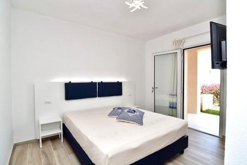 a white bedroom with a bed and a sliding glass door at Le Spiagge di San Teo in San Teodoro