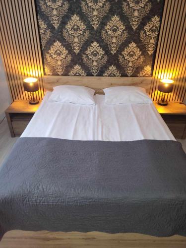 a bedroom with a large bed with two lamps on both sides at Willa "Aparthause" E-Apartamenty in Mielec