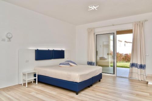a white bedroom with a bed and a sliding glass door at Le Spiagge di San Teo in San Teodoro