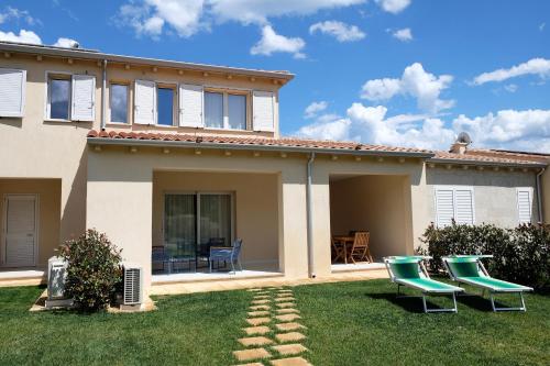 a house with two green chairs in the yard at Le Spiagge di San Teo in San Teodoro