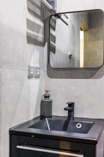 une salle de bain avec un lavabo noir et un miroir dans l'établissement Le Darcy - Standing - Centre-ville, à Dijon