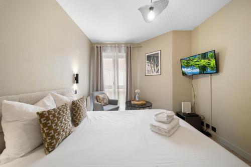 - une chambre avec un lit blanc et une télévision murale dans l'établissement Le Darcy - Standing - Centre-ville, à Dijon