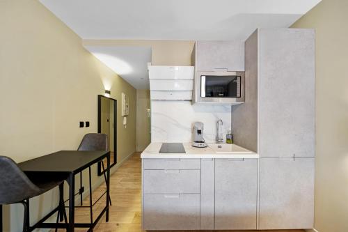une cuisine avec des armoires blanches et une table avec des chaises dans l'établissement Le Darcy - Standing - Centre-ville, à Dijon