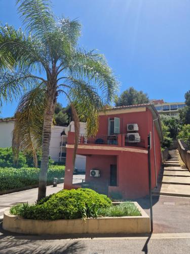 a red house with a palm tree in front of it at Roquebrune : Appartement 4 personnes proche de la plage (AV) in Roquebrune-Cap-Martin