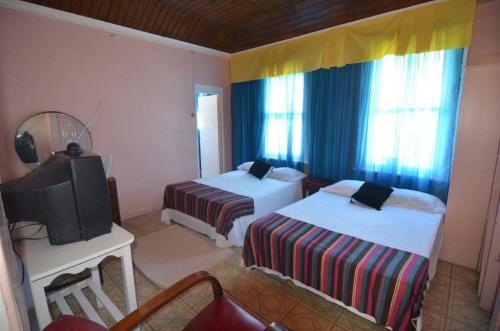 a hotel room with two beds and a television at Holiday Home - Guest House in Port Antonio
