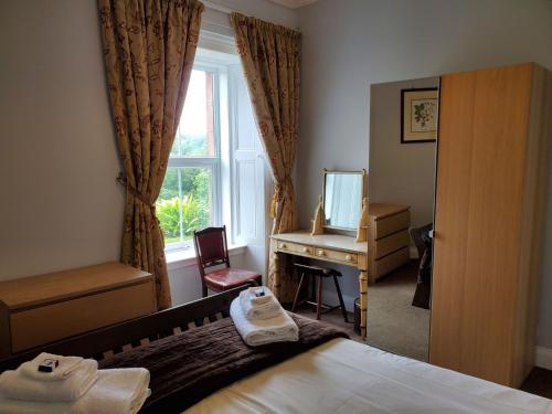 a bedroom with a bed and a desk and a window at McCaig's View in Oban